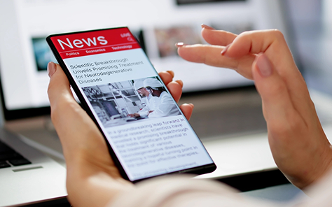 A hand holding a phone showing a semiconductor research news story